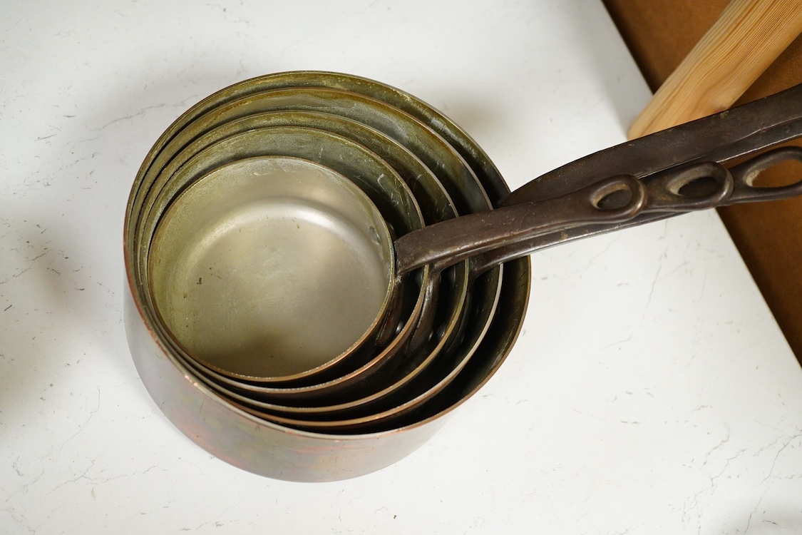 A graduated set of five copper saucepans